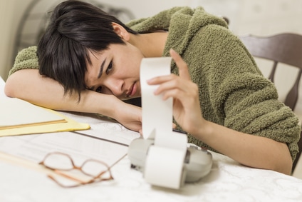 Mixed Race Young Female Agonizing Over Financial Calculations in Her Kitchen.