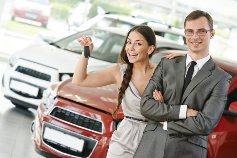 Happy young couple with keys from new car