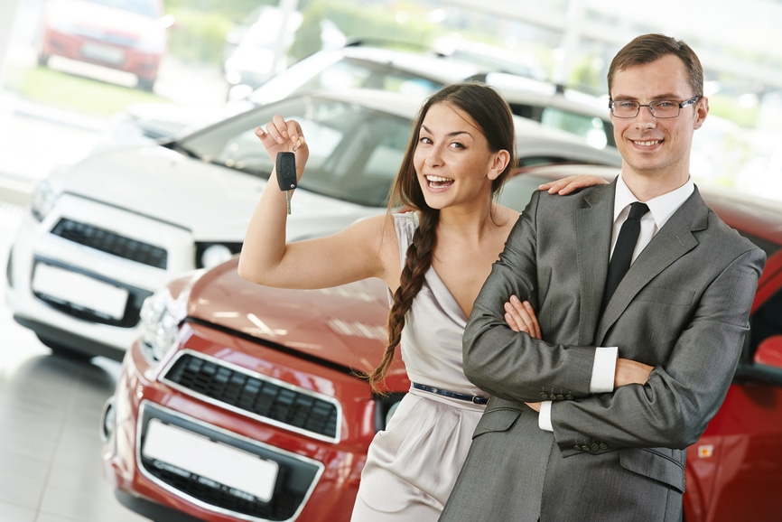 Happy young couple with keys from new car 