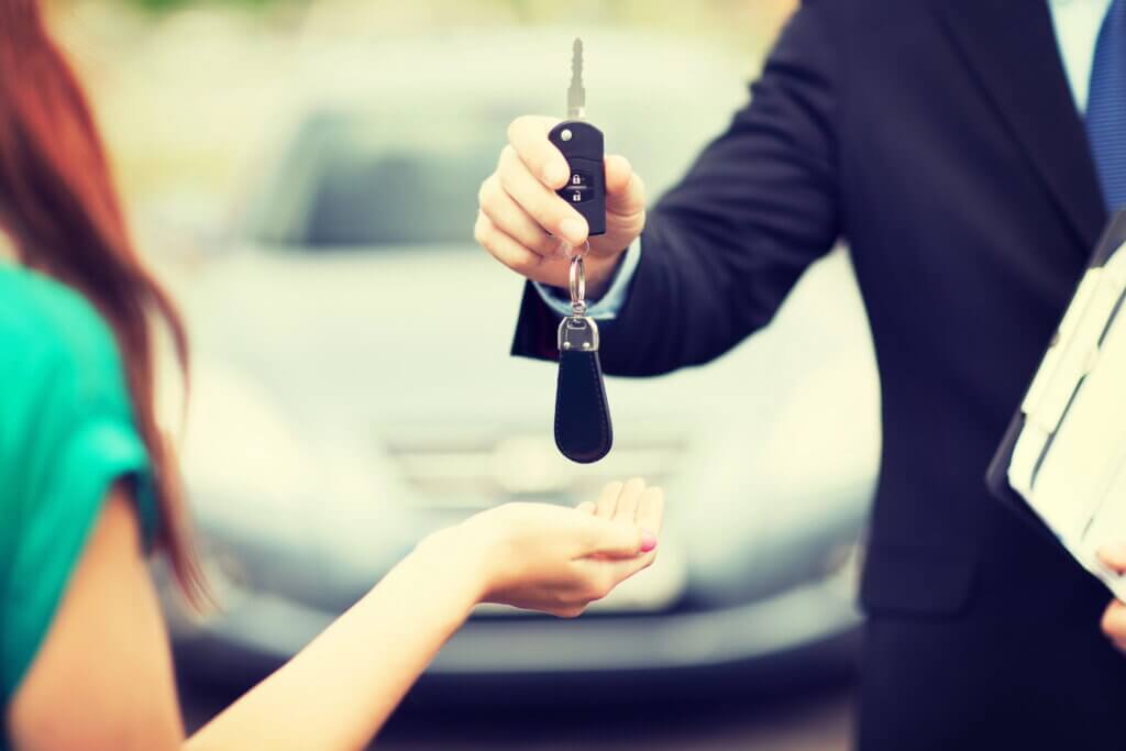 Man handing car keys to young woman, close-up
