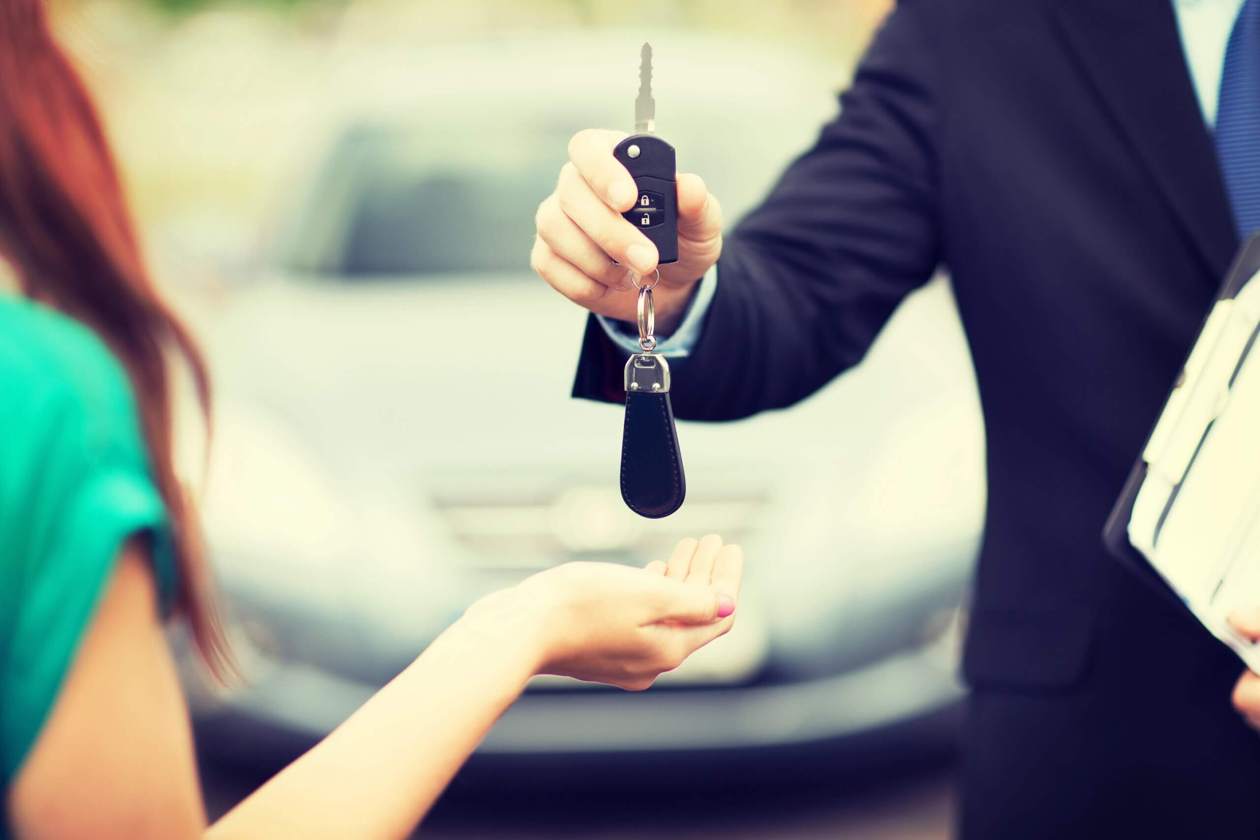Man handing car keys to young woman, close-up