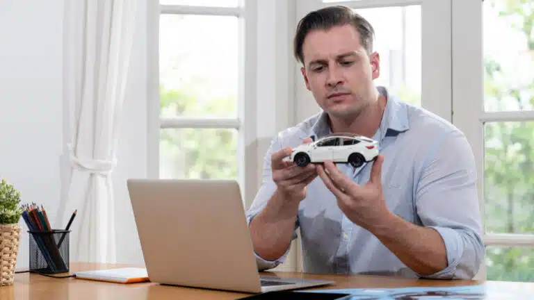 Man holding a model car at his desk.
